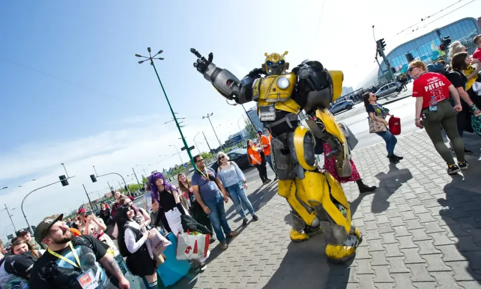 Bumblebee wita fanów na Pyrkonie. Tłum ludzi w kostiumach i z torbami idzie chodnikiem.
