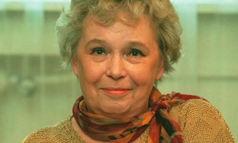 Uśmiechnięta Joanna Chmielewska, autorka kultowych powieści kryminalnych, w beżowym swetrze i kolorowym szalu.