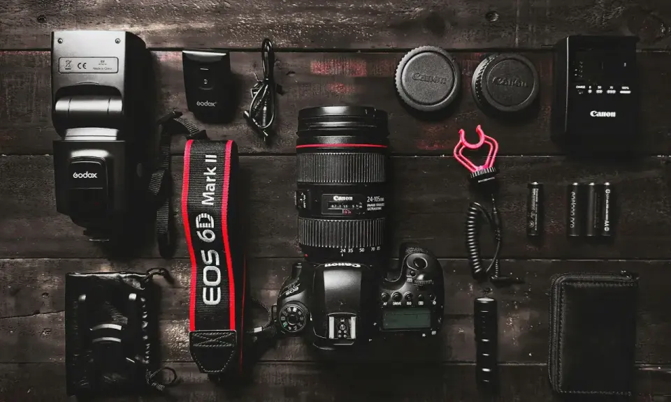 Zestaw fotograficzny: aparat Canon EOS 6D Mark II z obiektywem, lampa błyskowa, baterie i akcesoria. Podstawa aparatu fotograficznego gotowa do pracy.