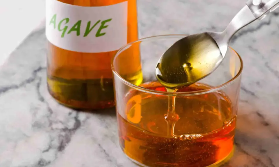 Sirope de agave en un vaso, con una cuchara vertiendo más. Ideal para endulzar recetas durante el embarazo.