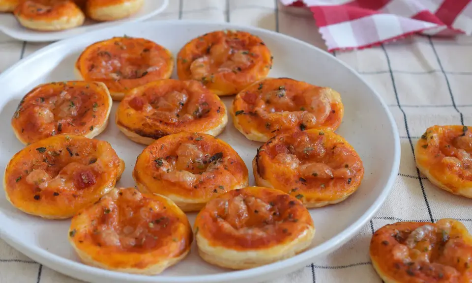 Deliciosas galletas de hojaldre con salsa de tomate y queso, perfectas para un aperitivo.