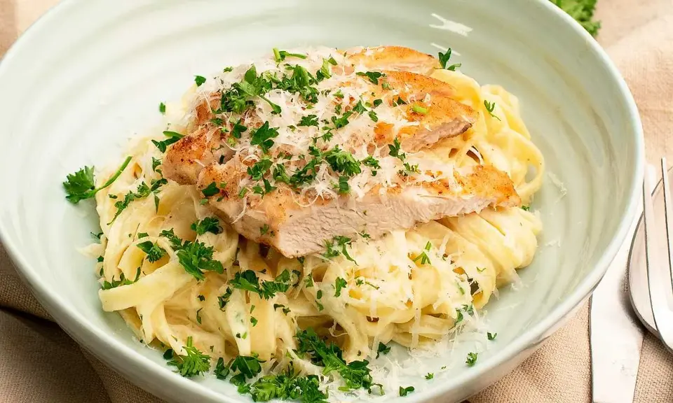 En krämig kyckling alfredo med tagliatelle, toppad med grillad kyckling, parmesan och färsk persilja. Ett perfekt recept för en snabb middag.