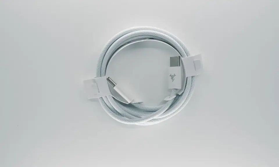 Biały kabel usb typu c, zwinięty w okrąg, z metalowymi końcówkami i logo producenta.