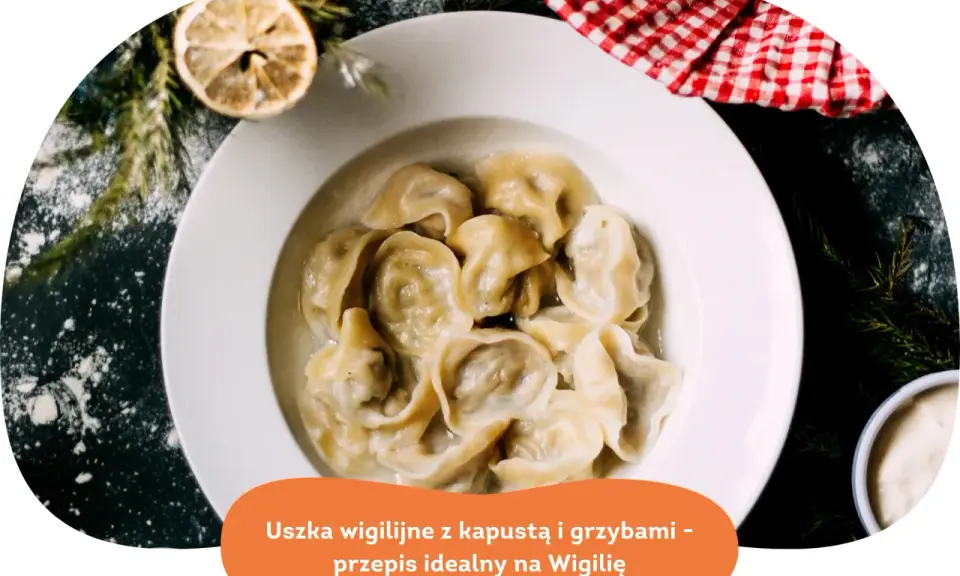 Pyszne uszka z grzybami, idealne na Wigilię, podane w białej misce, ozdobione gałązkami choinki i plasterkiem cytryny.