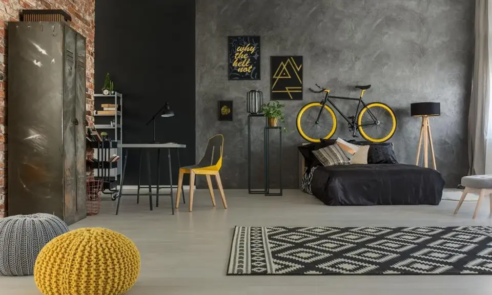 Kreatywne rozwiązanie, gdzie trzymać rower w bloku: zawieszony nad łóżkiem. Styl industrialny, czarno-żółta kolorystyka.