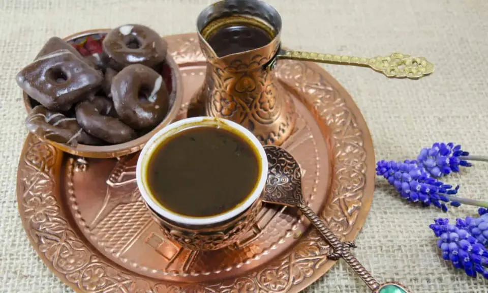 Ein traditionelles Mokkakännchen mit starkem Kaffee, dazu Schokoladenkekse und blaue Blumen. Was ist Mokka? Ein Genuss für die Sinne.