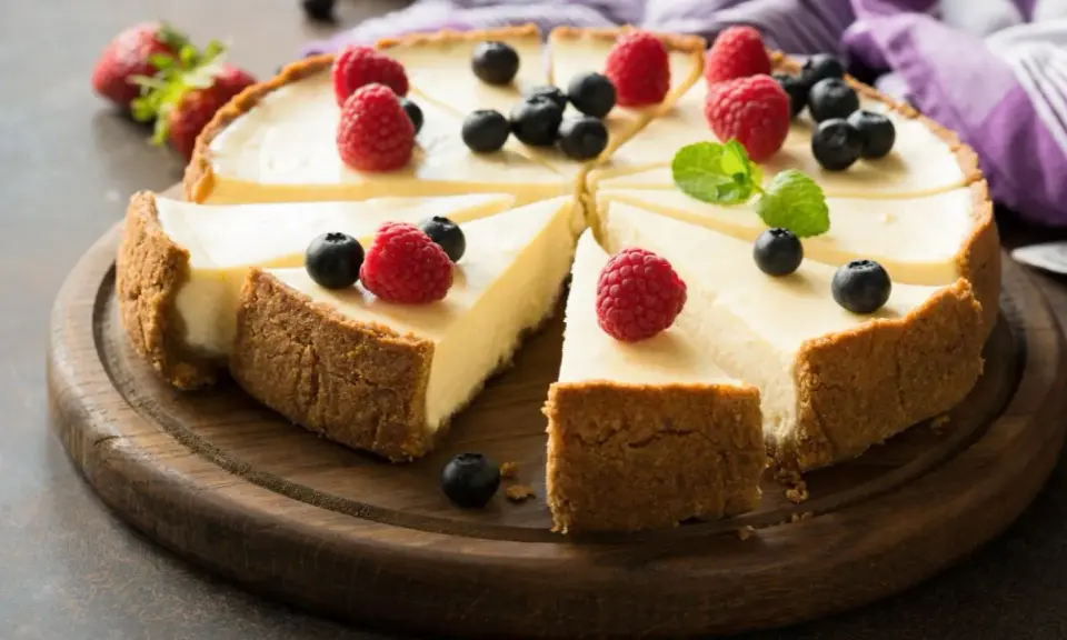 Pyszna tarta sernikowa z malinami i borówkami na drewnianej desce.