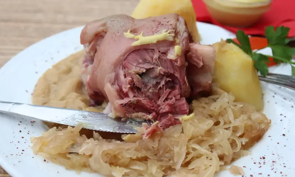 Un plat copieux de spécialités culinaires alsaciennes : jarret de porc, purée de pommes de terre et choucroute, garni de moutarde.