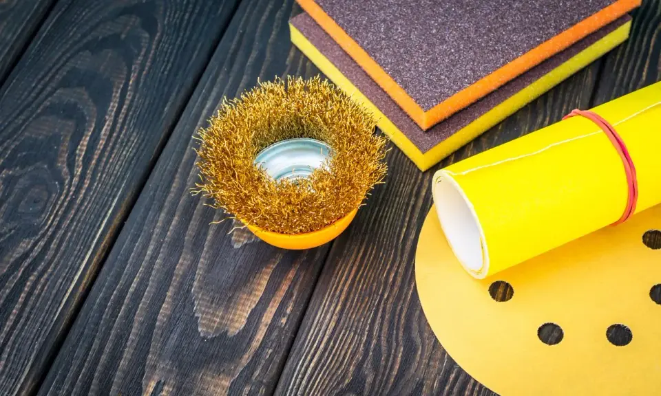 Outils de ponçage : brosse métallique, éponges abrasives et papier de verre pour préparer une surface en polyester avant l'application d'époxy.