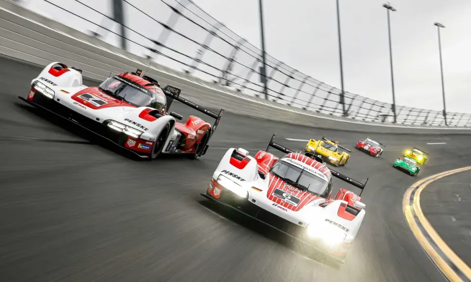 Mehrere Rennwagen, darunter ein weiß-roter Porsche, rasen auf der Strecke des 24-Stunden-Rennens von Daytona.