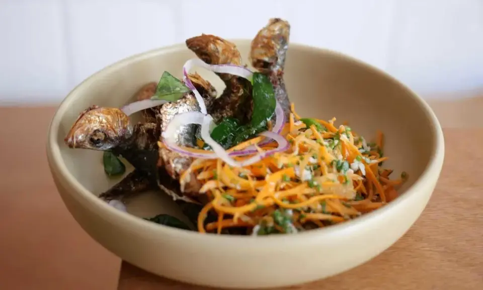 Poisson frit croustillant avec salade de carottes râpées et oignons rouges, une spécialité du restaurant la joie.