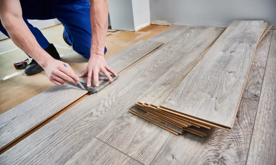 Handwerker misst Laminat für die Verlegung. Die Kosten für Laminat verlegen sind oft überschaubar.