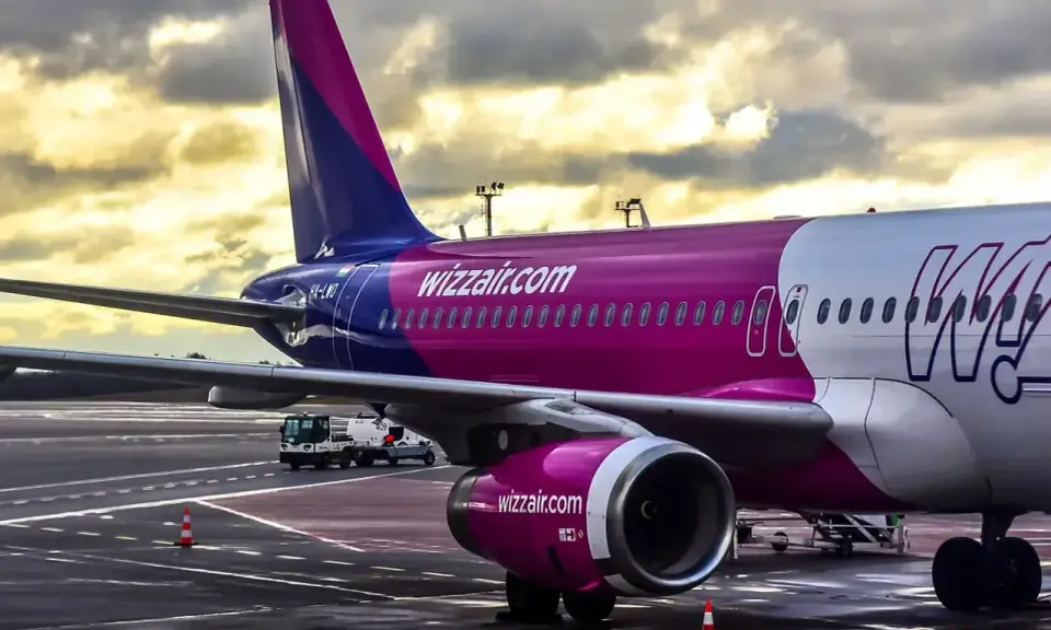 Samolot Wizz Air na płycie lotniska pod pochmurnym niebem.