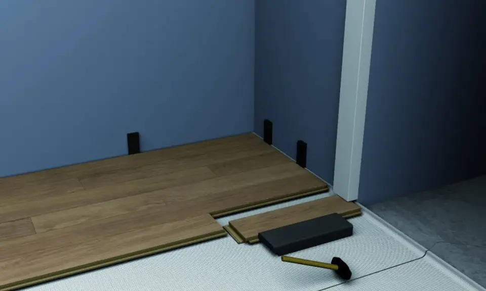 Instalación de suelo laminado. Se ven piezas de madera, un mazo y soportes para el rodapié que es la pieza final.