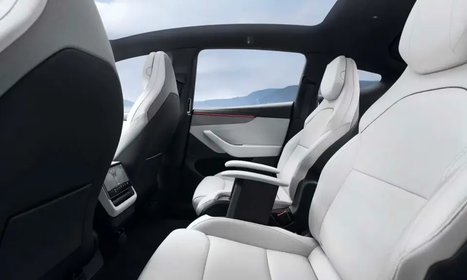 Interni bianchi e neri del Tesla Model Y, con sedili in pelle, tetto panoramico e vista sulle montagne.