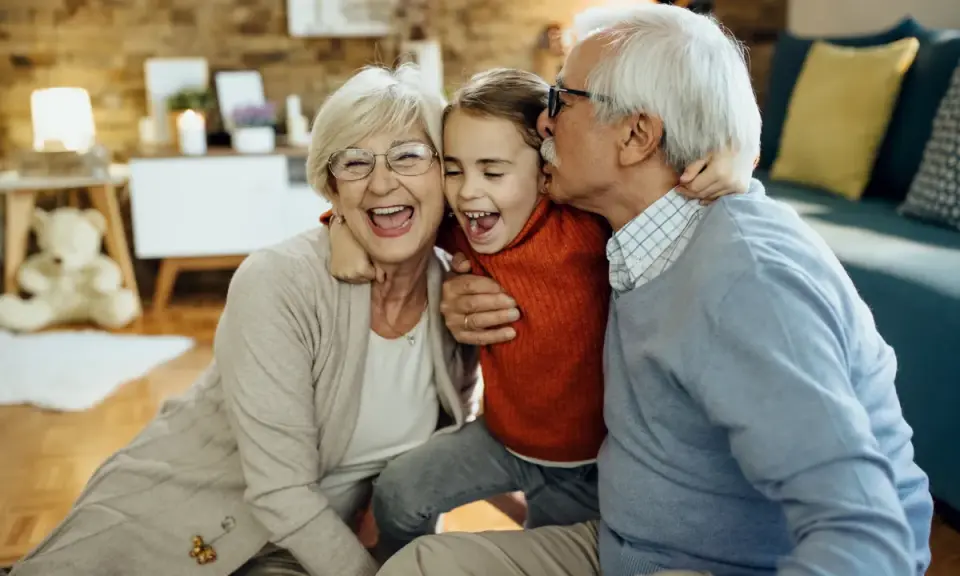 Abuelos riendo y abrazando a su nieta. Un momento tierno que demuestra la alegría de los padres que dejan a sus hijos con los abuelos.