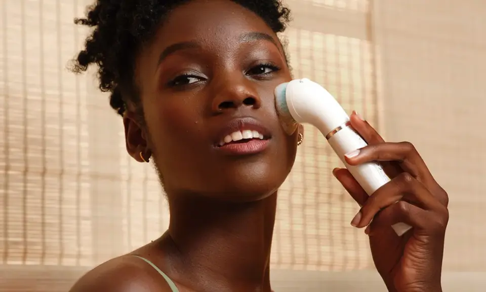 Donna con spazzola elettrica per esfoliazione viso, per una pelle luminosa e pulita.