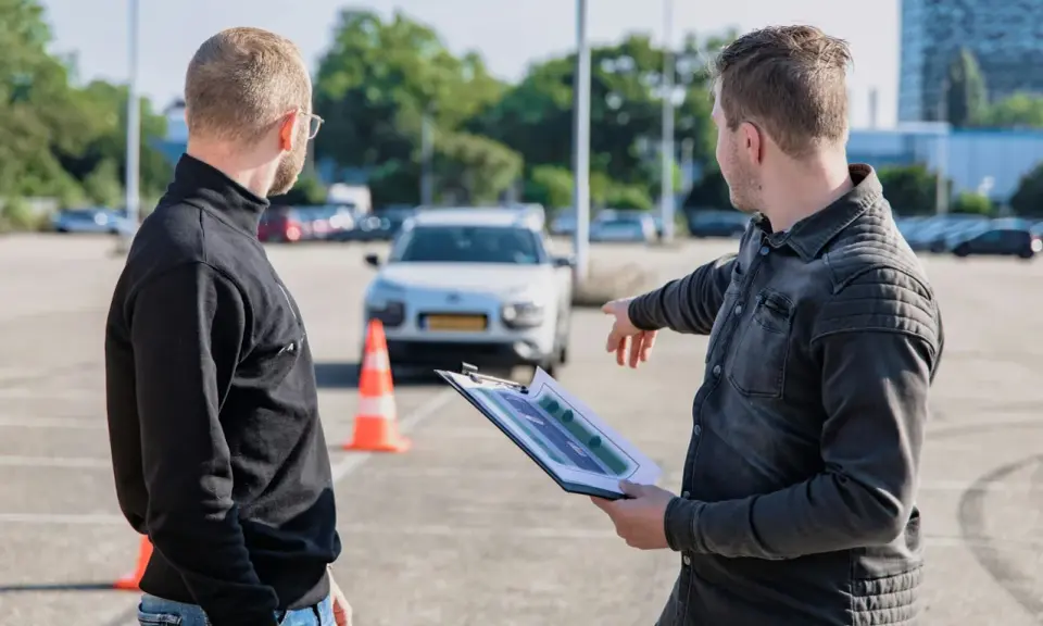 Instruktor omawia z kursantem plan trasy, świętując jego pozytywny wynik egzaminu teoretycznego.