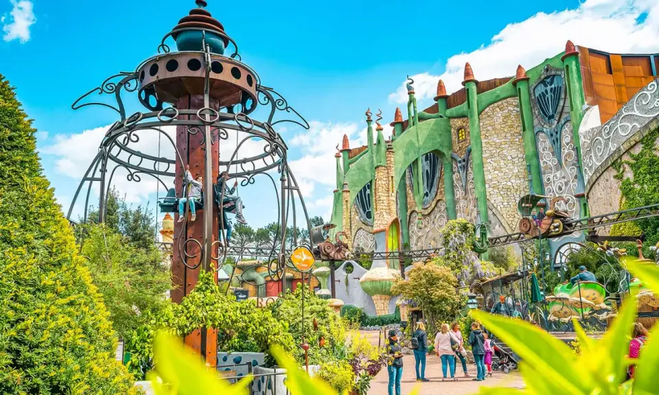 Phantasialand: Kettenkarussell und grüne Fantasiegebäude mit Achterbahn.