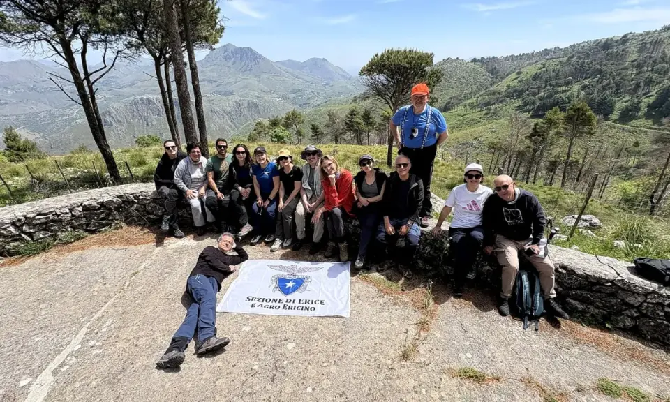 Gruppo di escursionisti con bandiera della Sezione di Erice e Agro Ericino, in cima al monte Gradara, con vista panoramica sulla valle.