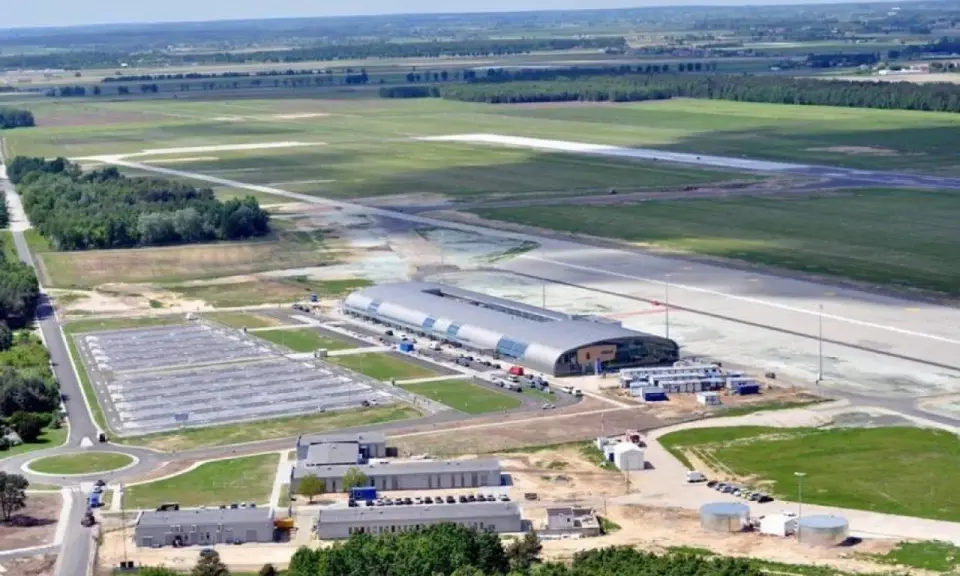 Lotnisko Warszawa Modlin z lotu ptaka: nowoczesny terminal, pas startowy i rozległe tereny zielone.