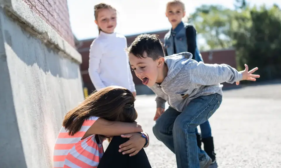 Niña acosada por otros niños en la calle.