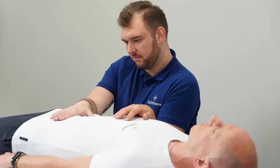 Terapeuta wykonuje zabieg z zakresu osteopatii wisceralnej, delikatnie dotykając brzucha pacjenta.