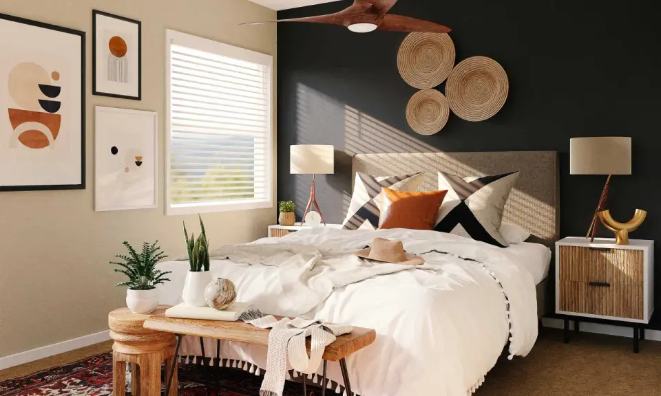 Une chambre moderne avec une décoration murale en vannerie, des tableaux abstraits et un ventilateur de plafond. Le lit est fait de blanc, avec des coussins graphiques et une touche de couleur ocre.