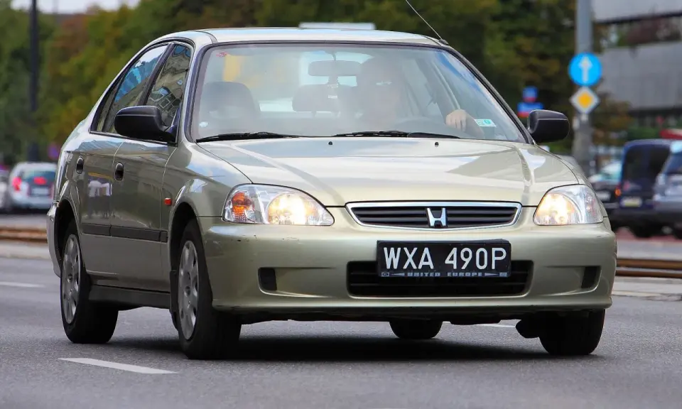Złoty sedan Honda Civic z widocznym numerem rejestracyjnym WXA 490P. Brak tablicy rejestracyjnej z przodu.