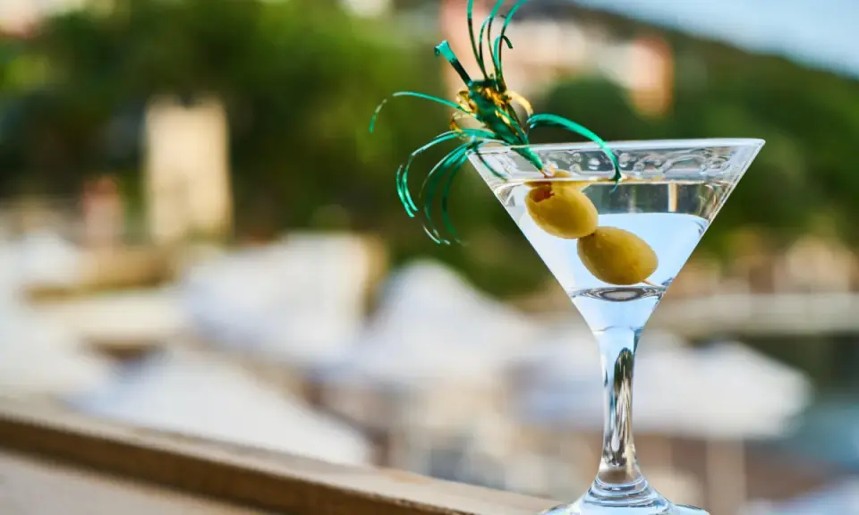 Elegancki kieliszek martini z dwiema oliwkami i zieloną ozdobą. Idealny na toast "cin cin fiero" w letni wieczór.