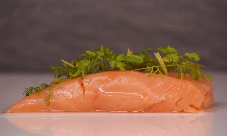 Zartes Lachsfilet, sous vide gegart, mit frischen Kräutern und Zitronenzesten garniert.