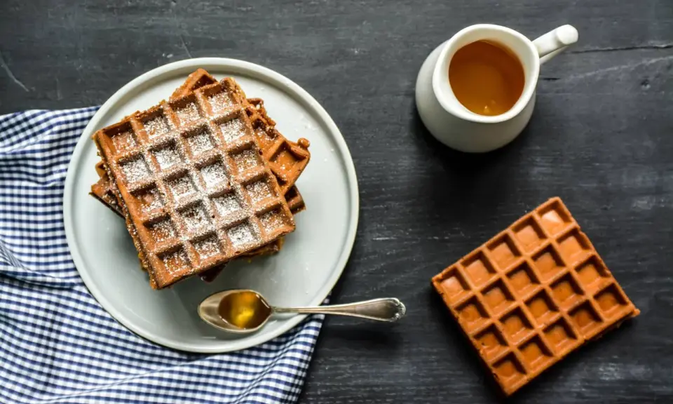 Gaufres de farine de châtaigne saupoudrées de sucre glace, servies avec du miel doré. Un délice gourmand.