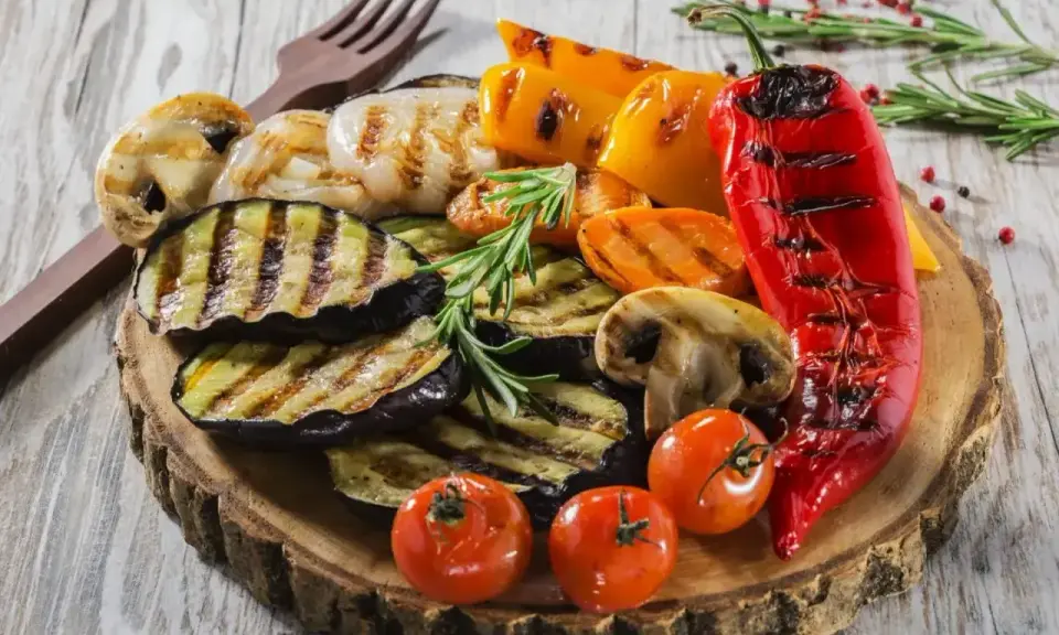 Pyszne warzywa na grilla: grillowany bakłażan, papryka, pieczarki, pomidorki i czerwona papryka, udekorowane rozmarynem.