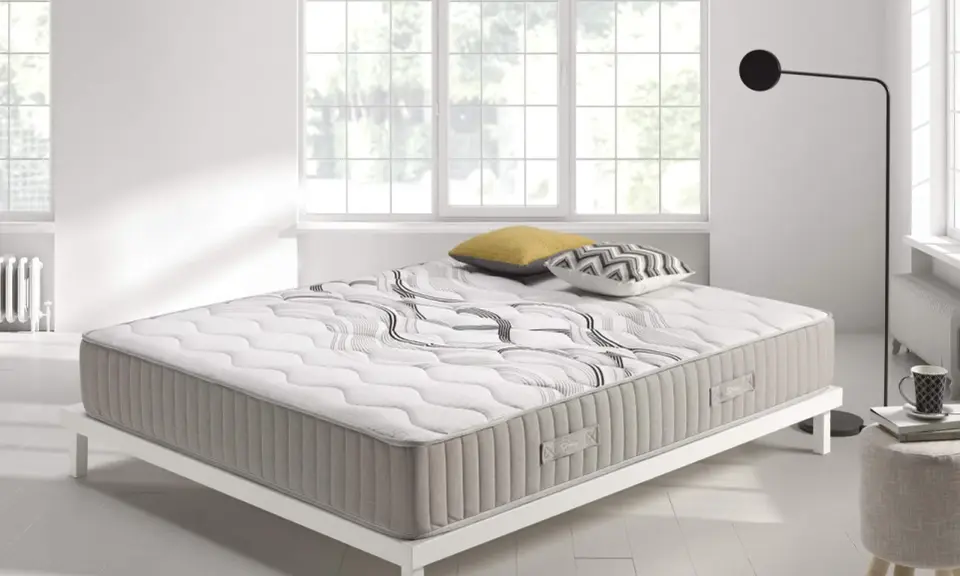 Colchón con diseño moderno sobre base blanca, ideal para quienes buscan confort y soporte. ¿Que es mejor para la espalda muelles o visco?