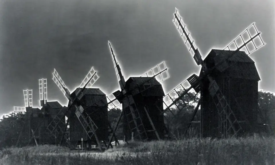 Mulini a vento in un campo, con un effetto di solarizzazione man ray che illumina le pale.