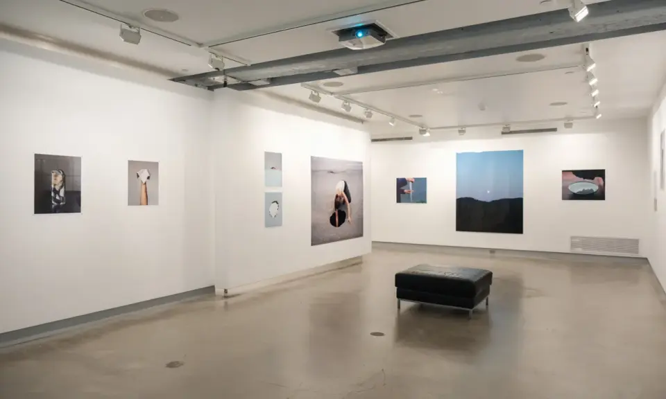 Art exhibition at blue sky gallery Portland, featuring abstract photography and a black leather ottoman.