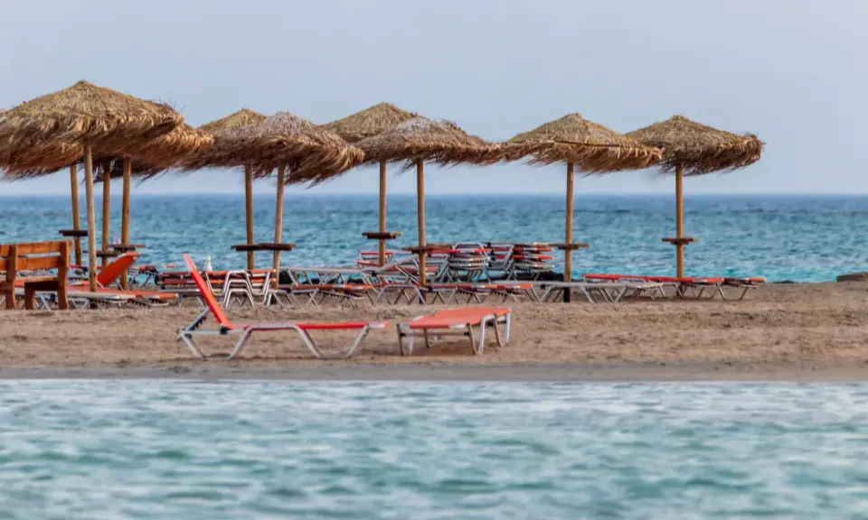 Plaża Elafonisi z rzędem słomianych parasoli i leżaków, gotowa na gości.