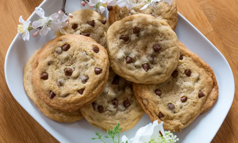 Schokoladenkekse, die an das Subway Cookies Rezept erinnern, auf einem Teller mit Kirschblüten.