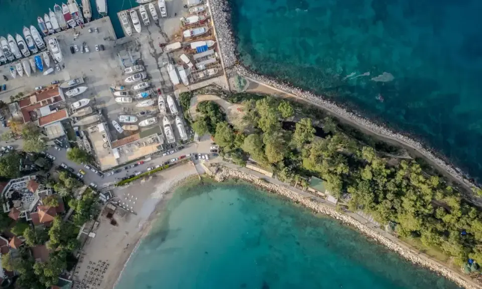 Widok z lotu ptaka na port i plażę w Kemerze. Widać liczne jachty i łodzie, a także zielony teren z drzewami. To idealne miejsce na odkrywanie atrakcji Kemer Turcja.
