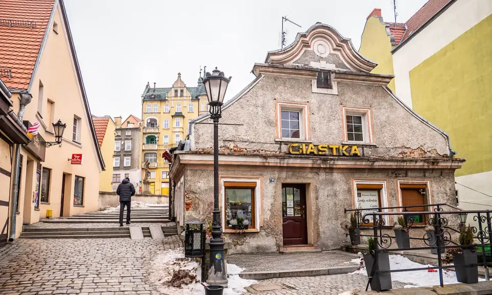 Kłodzko rynek. Kamienne uliczki i kolorowe kamienice tworzą urokliwy klimat. Na pierwszym planie budynek z napisem "Ciastka".