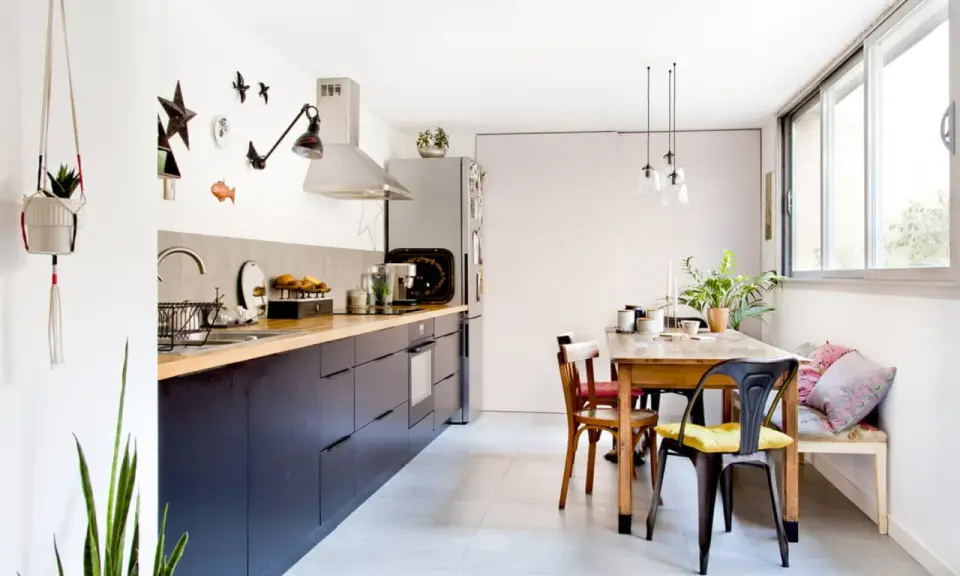 Cuisine sans placard haut, avec des meubles bas sombres, un plan de travail en bois et une table à manger.