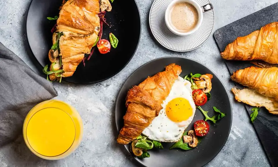 Typowe amerykańskie śniadanie: croissant z jajkiem sadzonym, pomidorkami i grzybami, do tego kawa i sok.