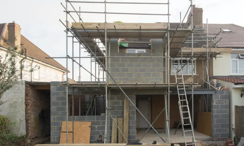 Construction d'une maison : échafaudages, blocs de béton, poutres métalliques. Penser à tout quand on fait construire sa maison.