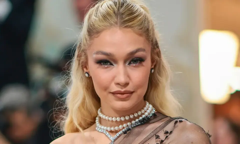 Gigi Hadid luce un maquillaje con perlas, con pequeños adornos brillantes en los ojos y un collar de perlas.