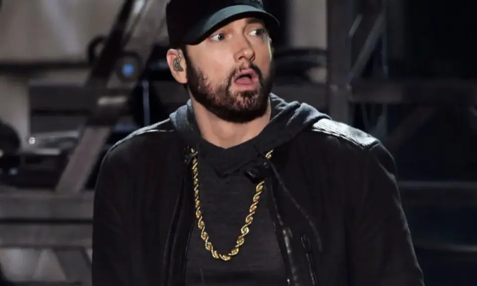 Eminem w czapce i złotej koli, z miną sugerującą zdziwienie, jakby usłyszał pytanie: czemu Eminem nie lubi Polski.