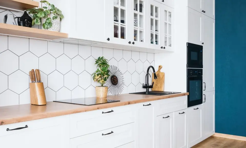 Cuisine moderne et lumineuse avec carrelage hexagonal blanc, plan de travail en bois et meubles blancs. Idéal pour refaire sa cuisine petit budget.