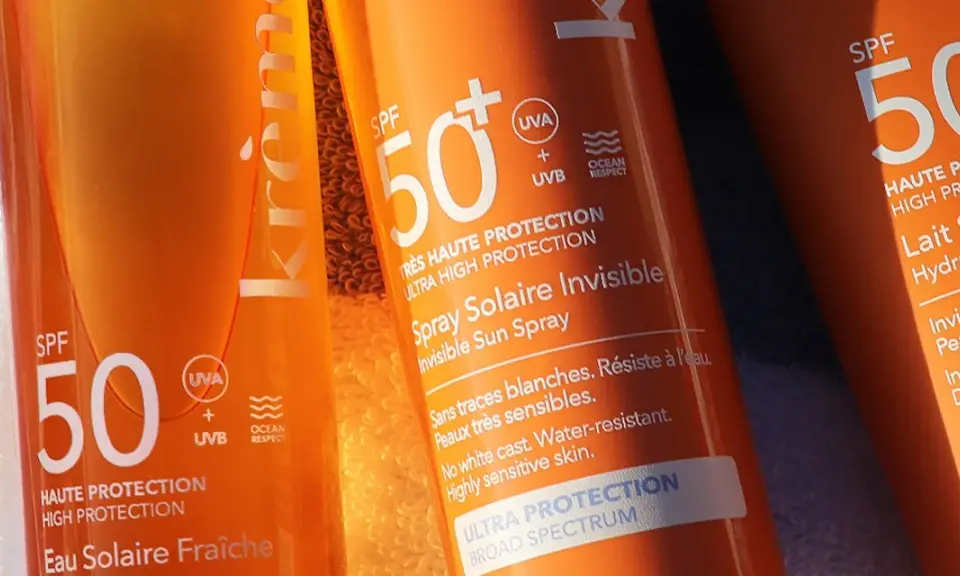 Trois tubes de crème solaire, tous avec SPF 50, prêts pour la protection solaire. L'un est un spray invisible, l'autre un lait hydratant.
