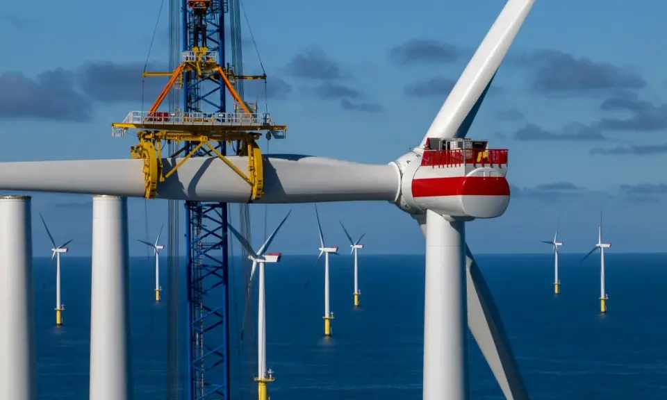 Bau eines Offshore-Windparks für die **Energie Niederlande**. Ein Kran hebt ein Rotorblatt einer riesigen Windkraftanlage im Meer.