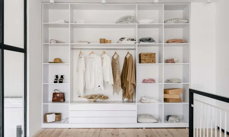 Idéal pour aménager un placard : étagères blanches remplies de vêtements, accessoires et boîtes.
