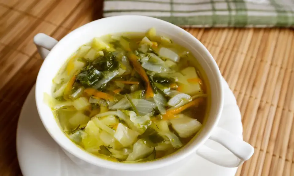 Aromaticzny kapuśniak z młodej kapusty, pełen warzyw i ziół, podany w białej miseczce.
